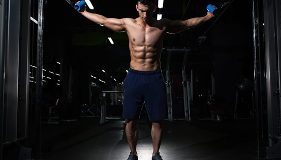Muscular Shredded male wearing a blue gym short preparing to do a cable crossover