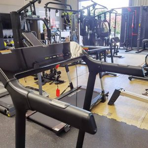 Cardio Equipment- (300*300) image- Cropped profile view of the Foldable Treadmill DB-2001 in a gym with console, handlebar and vertical frame in view along with various other equipment in frame