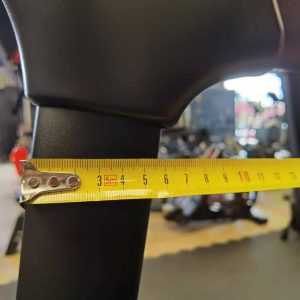 Cardio Equipment- Low resolution (300*300) image of detail view of the Foldable Treadmill DB-2001 in a Gym with a yellow measuring tape along the thickness of the vertical frame