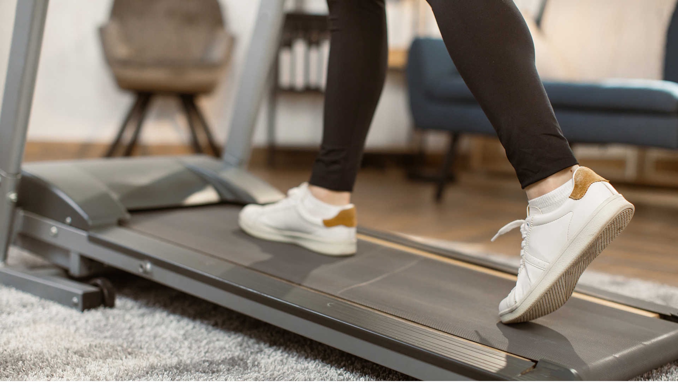 Woman using folding running machine in her living room space.